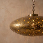 Close detail of the lit Agafay lantern hanging from its chain, hand-pierced pattern glowing