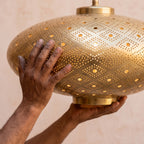 Maker's hands holding the unlit Agafay lantern in the workshop