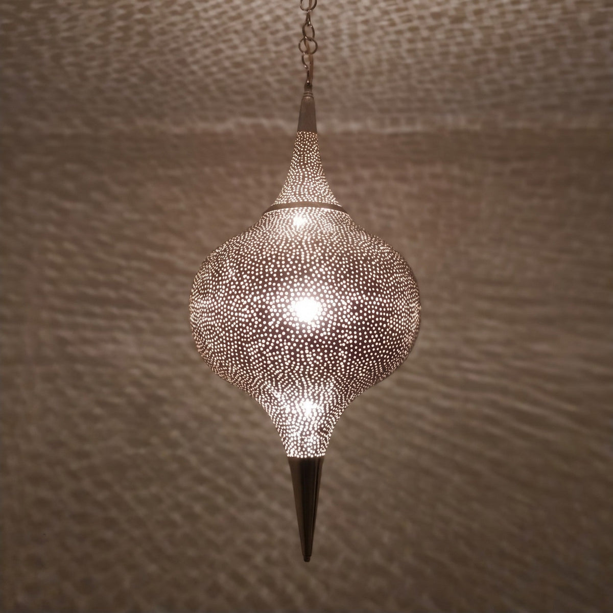 Close detail of the lit Aksil, warm light through hand-punched circles