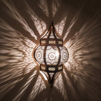 Close detail of the lit Amalu sconce, pattern and shadow on the wall behind