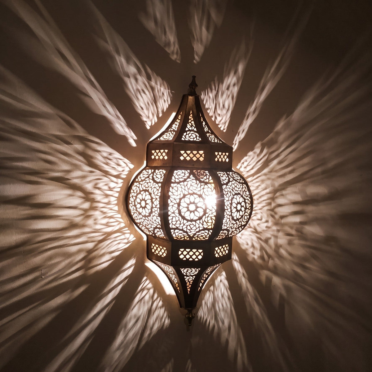 Close detail of the lit Amalu sconce, pattern and shadow on the wall behind