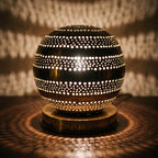 Close view of the lit Aman lamp, light escaping through hand-cut perforations
