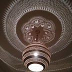 Detail of the lit Amanar pendant, leaf piercings glowing in the brass