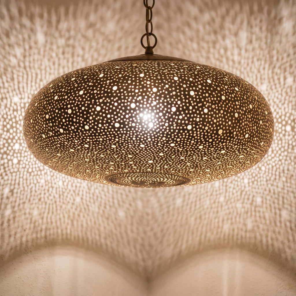 Close view of the lit Anfa pendant, light through the pierced brass