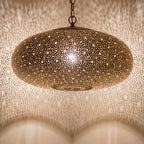 Close view of the lit Anfa pendant, light through the pierced brass