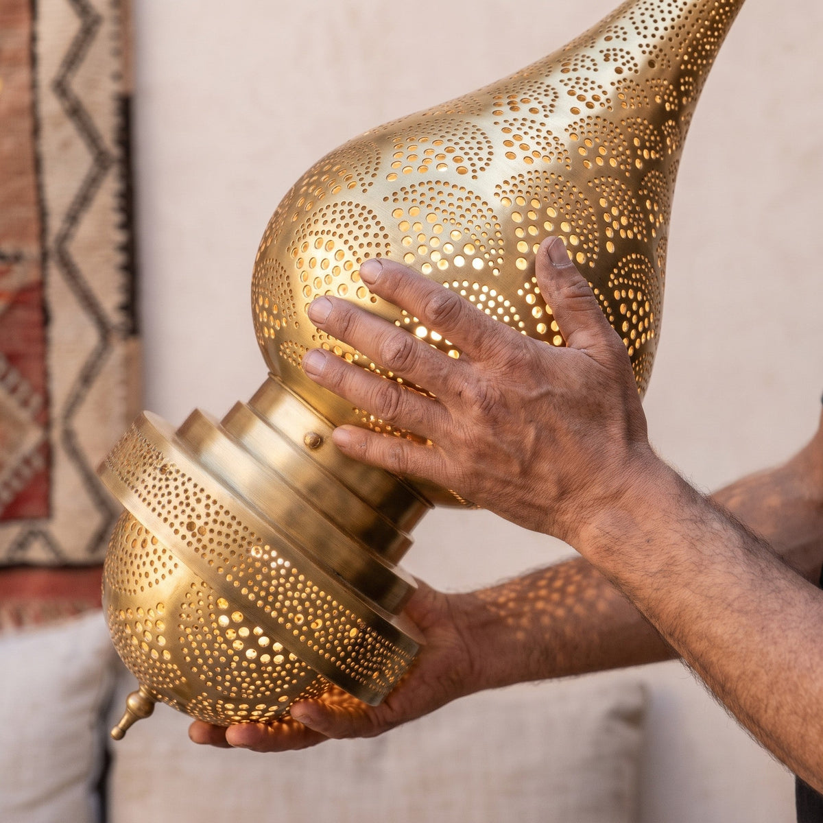 A maker's hands steadying the tall Asafu body in the workshop