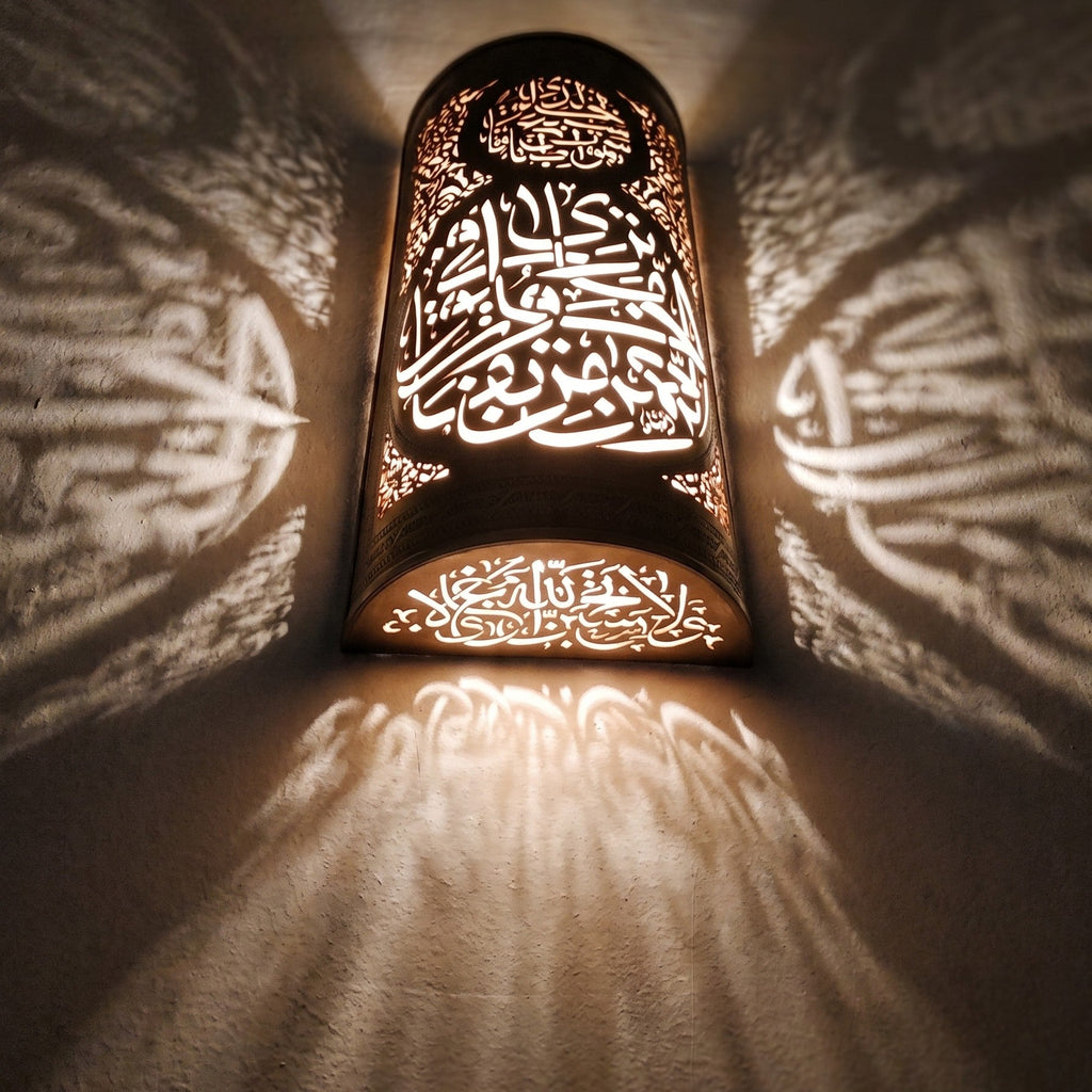 Lit Aya sconce up close, the pierced calligraphy glowing