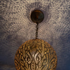 Close view of the lit Badr pendant, light coming through the pierced holes