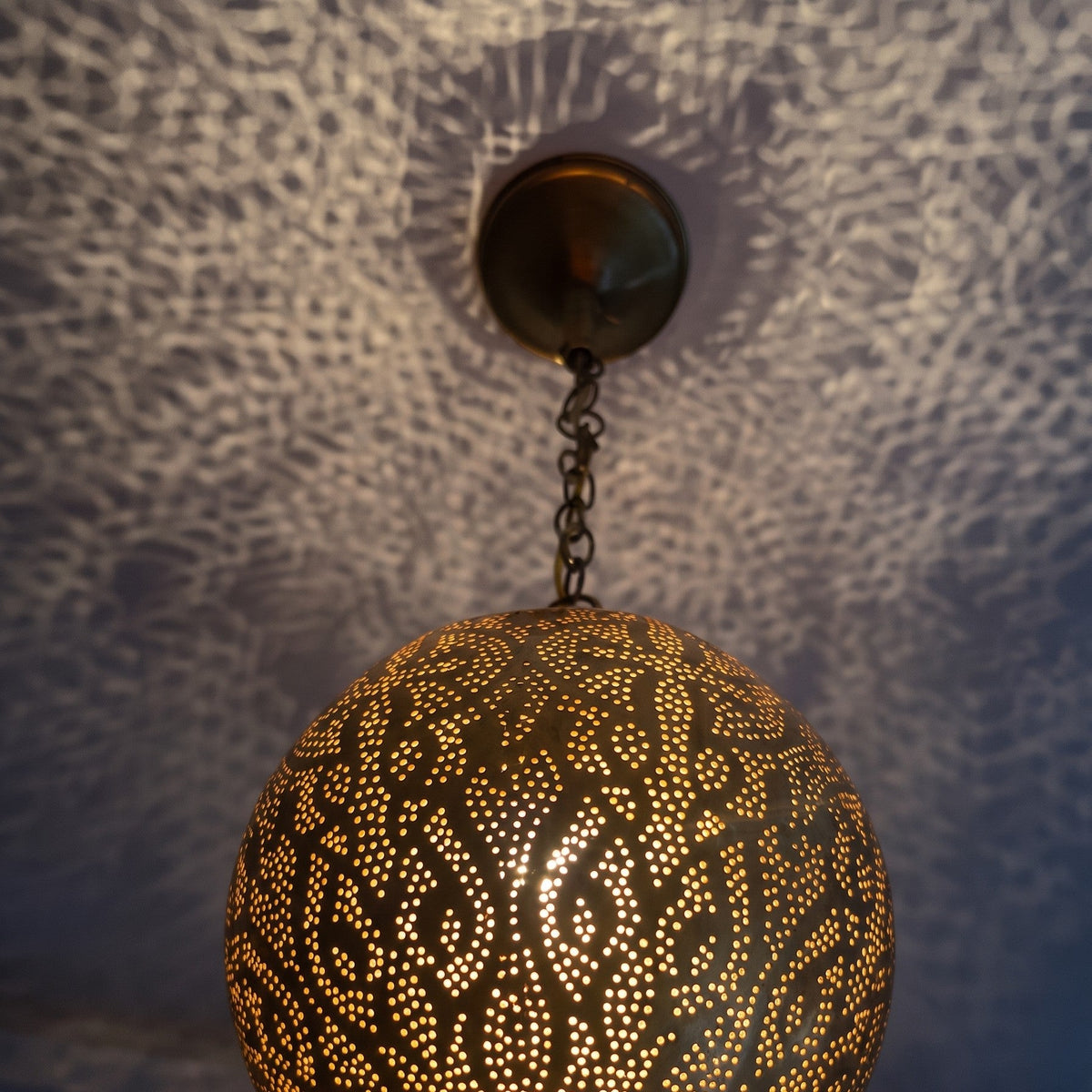Close view of the lit Badr pendant, light coming through the pierced holes