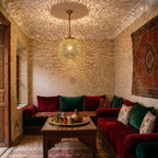 Bahia pendant glowing against carved plaster in a Moroccan riad