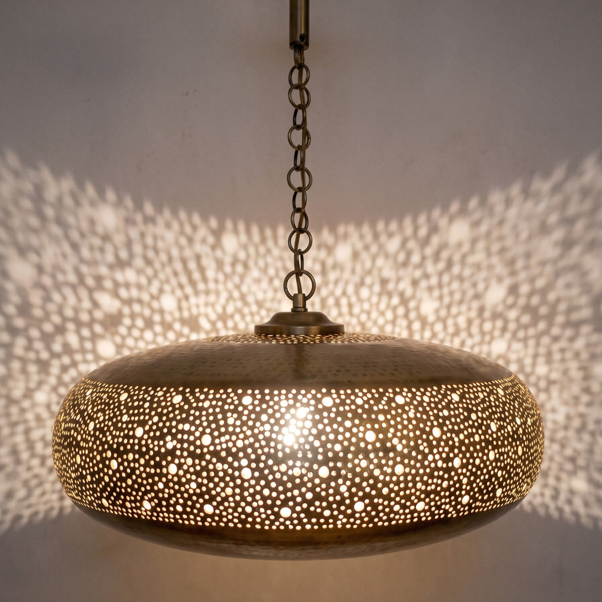Detail of the lit Dihya pendant showing light through a pierced floral band