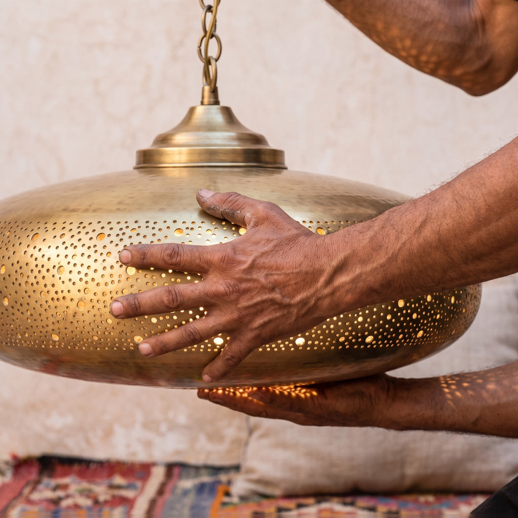 Artisan's hands holding the Dihya pendant shade in the workshop