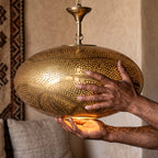 The Hana brass shade held in the maker's hands in the workshop