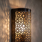 One Isli sconce lit in close-up, openwork glowing