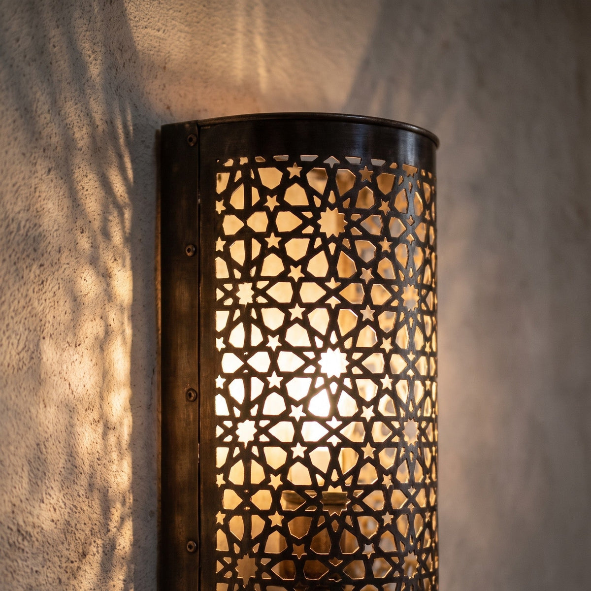 One Isli sconce lit in close-up, openwork glowing