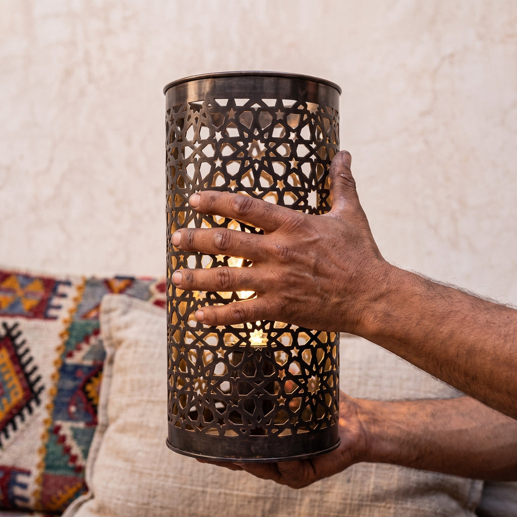 An Isli sconce held in the maker's hands, openwork toward the camera