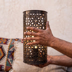 An Isli sconce held in the maker's hands, openwork toward the camera