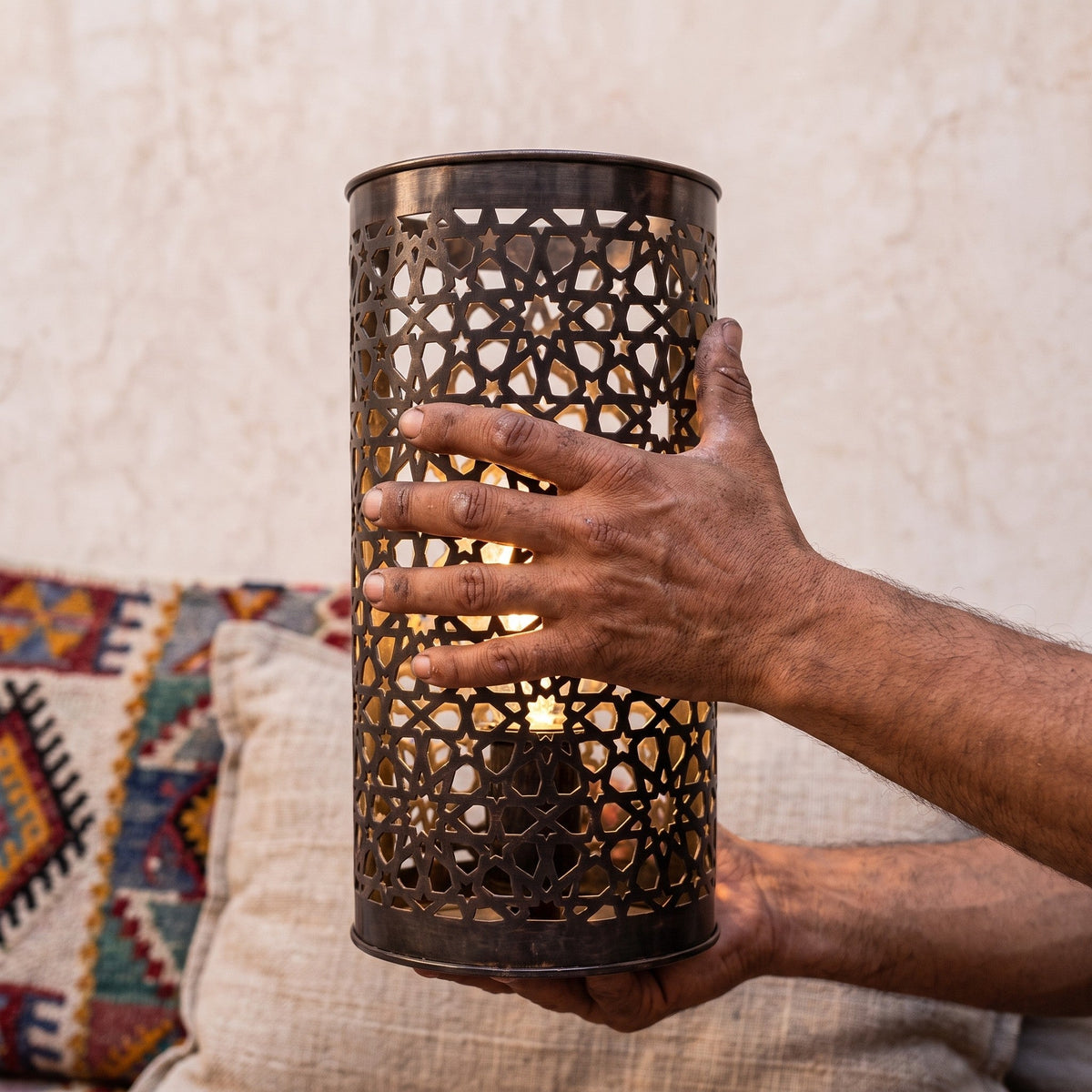An Isli sconce held in the maker's hands, openwork toward the camera