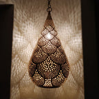Close view of the lit Itri pendant, light passing through hand-punched circles