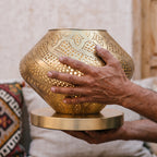Artisan's hands holding the opened Khzama lantern above the workbench