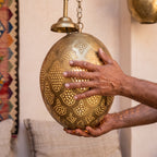 The Massa egg held in the maker's hands, punched pattern visible