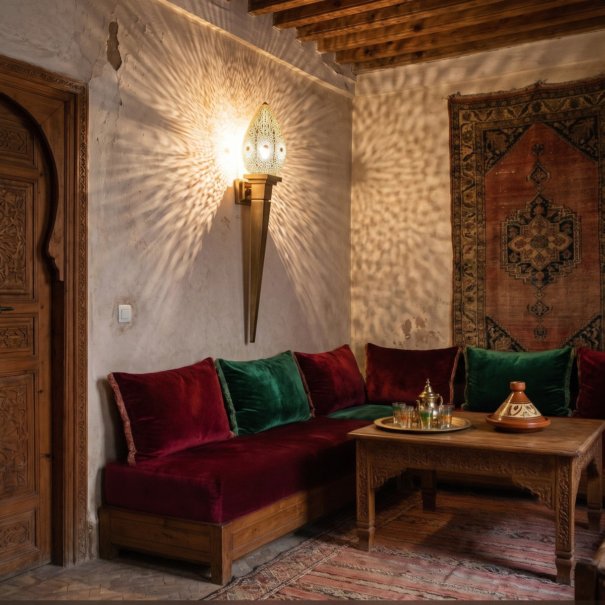 Menara sconce glowing on a riad wall at night, its pattern cast across the plaster