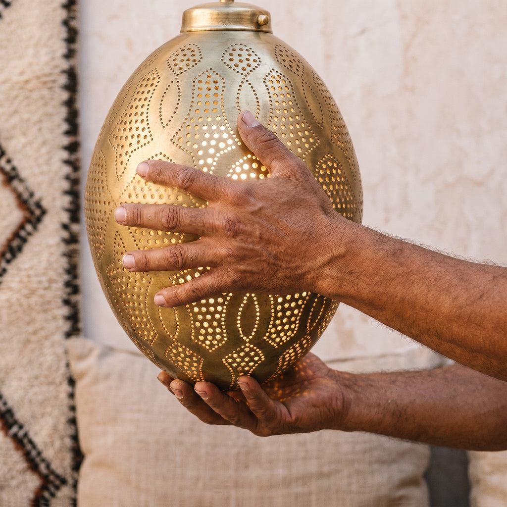 Maker's hands holding the Merzouga lantern in the workshop