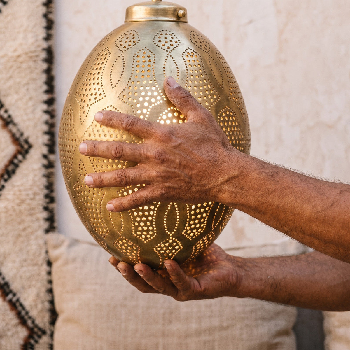 Maker's hands holding the Merzouga lantern in the workshop