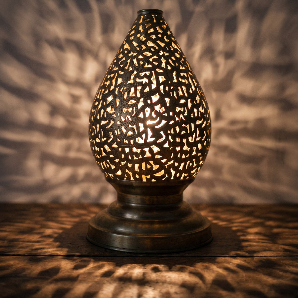Detail of the lit Naqsh lamp, light passing through hand-cut Arabic letters