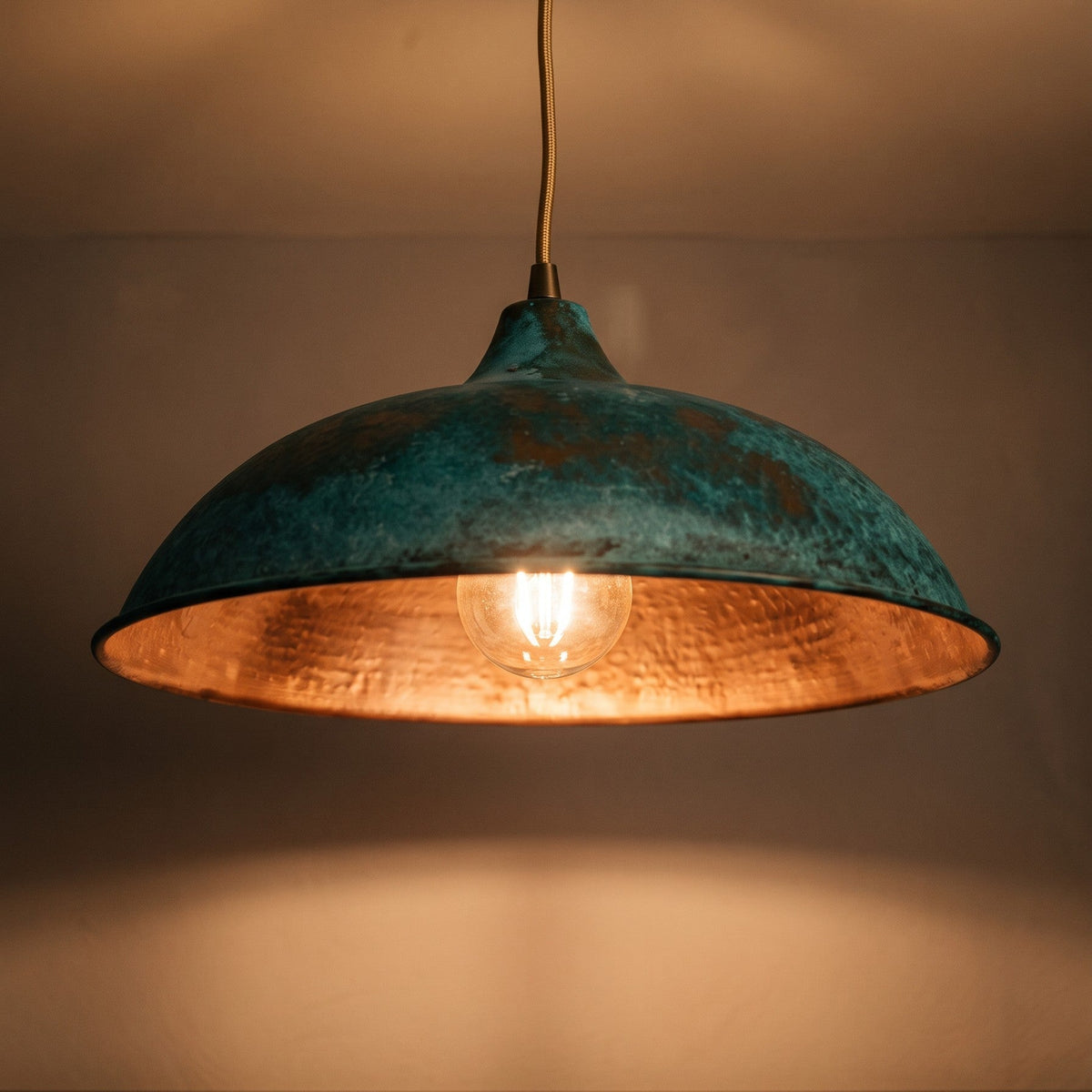 Close view of the lit Nila pendant, amber light inside the copper dome