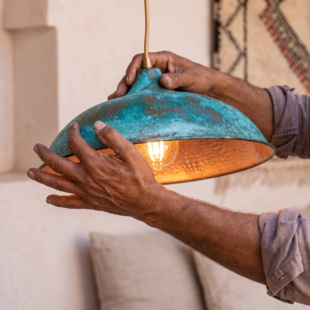Maker's hands holding the oxidized copper dome of the Nila pendant