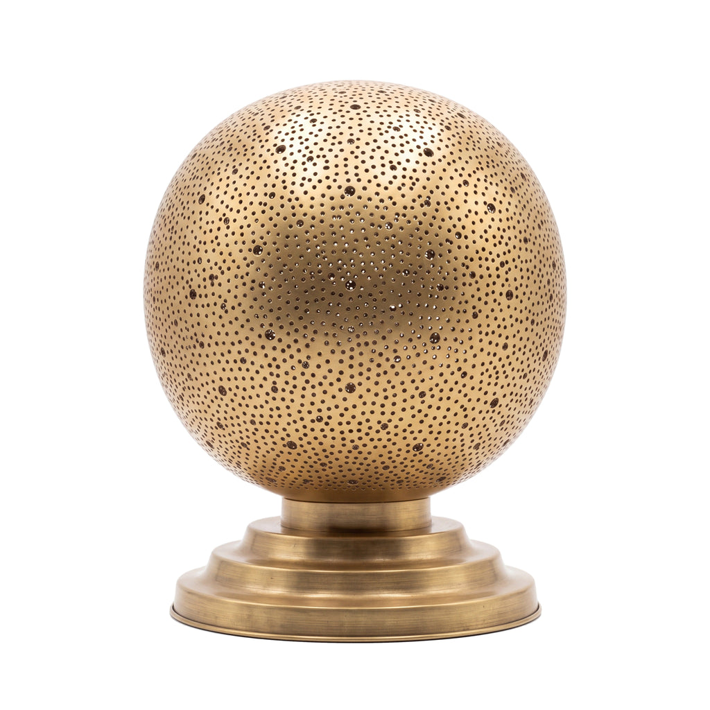 Ourika pierced brass globe table lamp on a white studio background