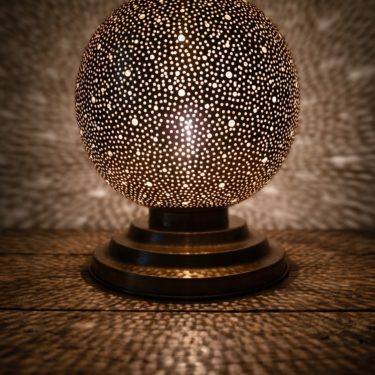 Detail of the lit Ourika globe, warm light through hand-perforated brass