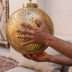 A maker's hands turning the Qamar sphere in the Marrakech workshop