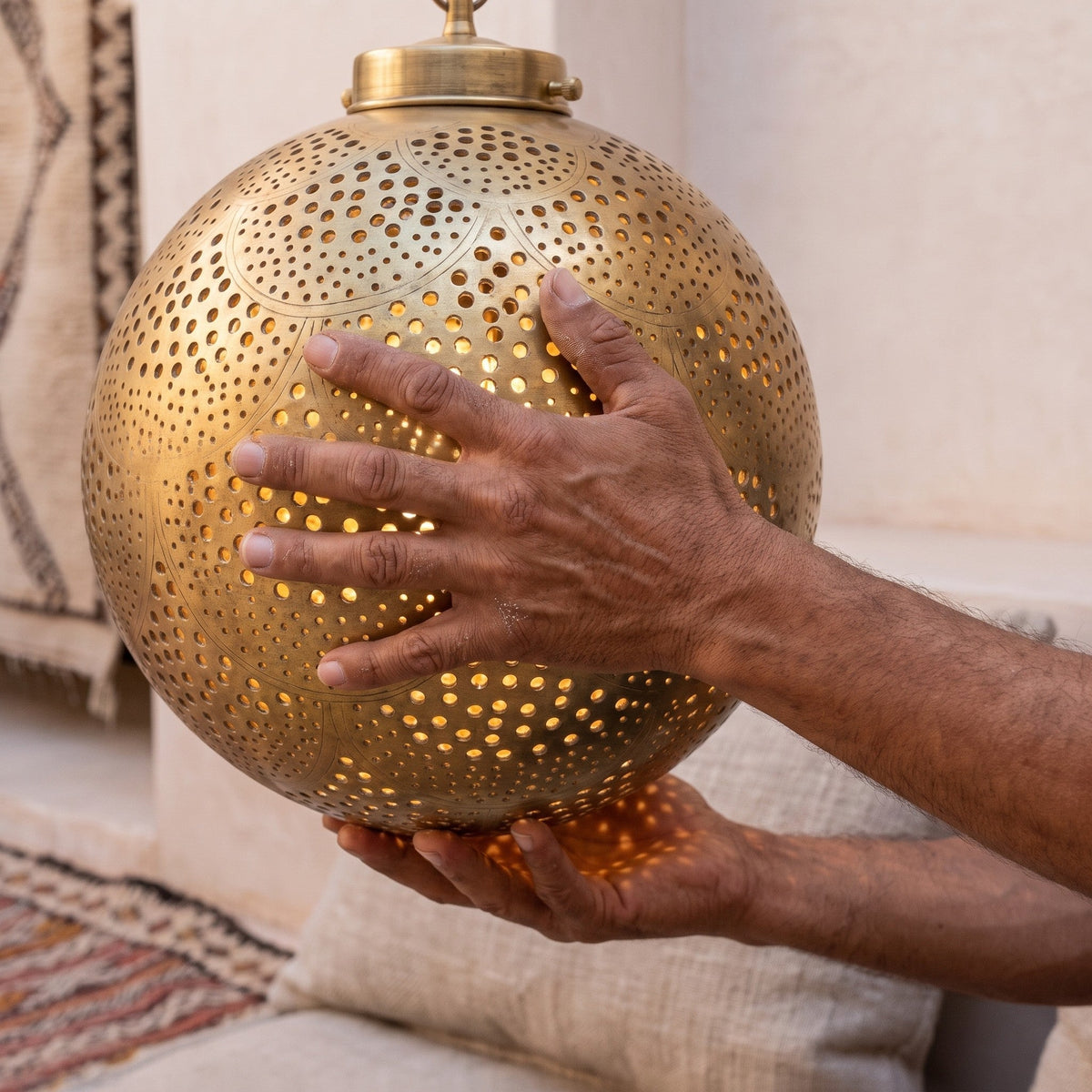 A maker's hands turning the Qamar sphere in the Marrakech workshop