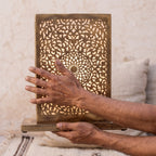 The maker's hands holding the engraved brass disc of the Sabah lamp