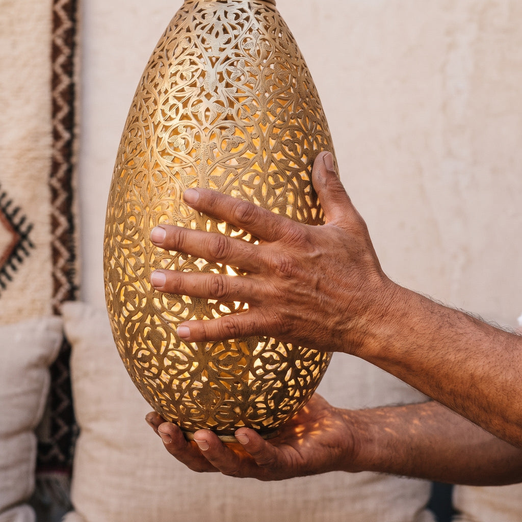 Maker's hands holding the corset-shaped brass body of the Sana sconce