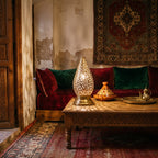 Shama lantern pair glowing on a low table in a Moroccan riad courtyard