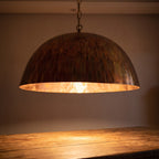 Close view of the lit Siniya pendant, engraving catching warm light at the copper rim