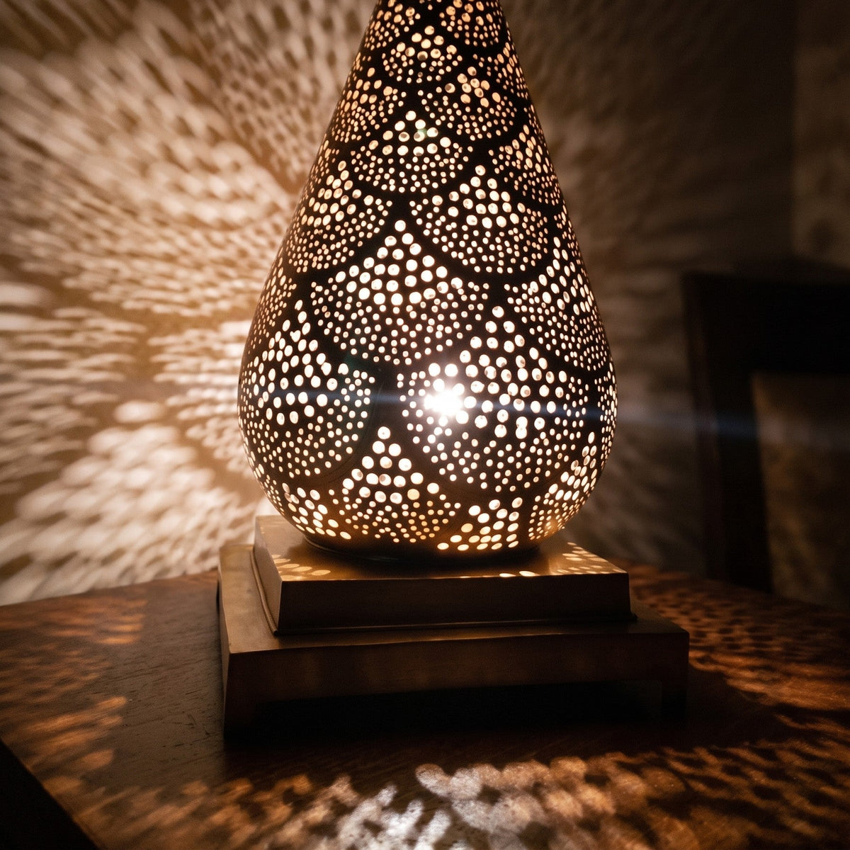 Detail of Siraj lit, bulb glowing behind the hand-pierced brass body