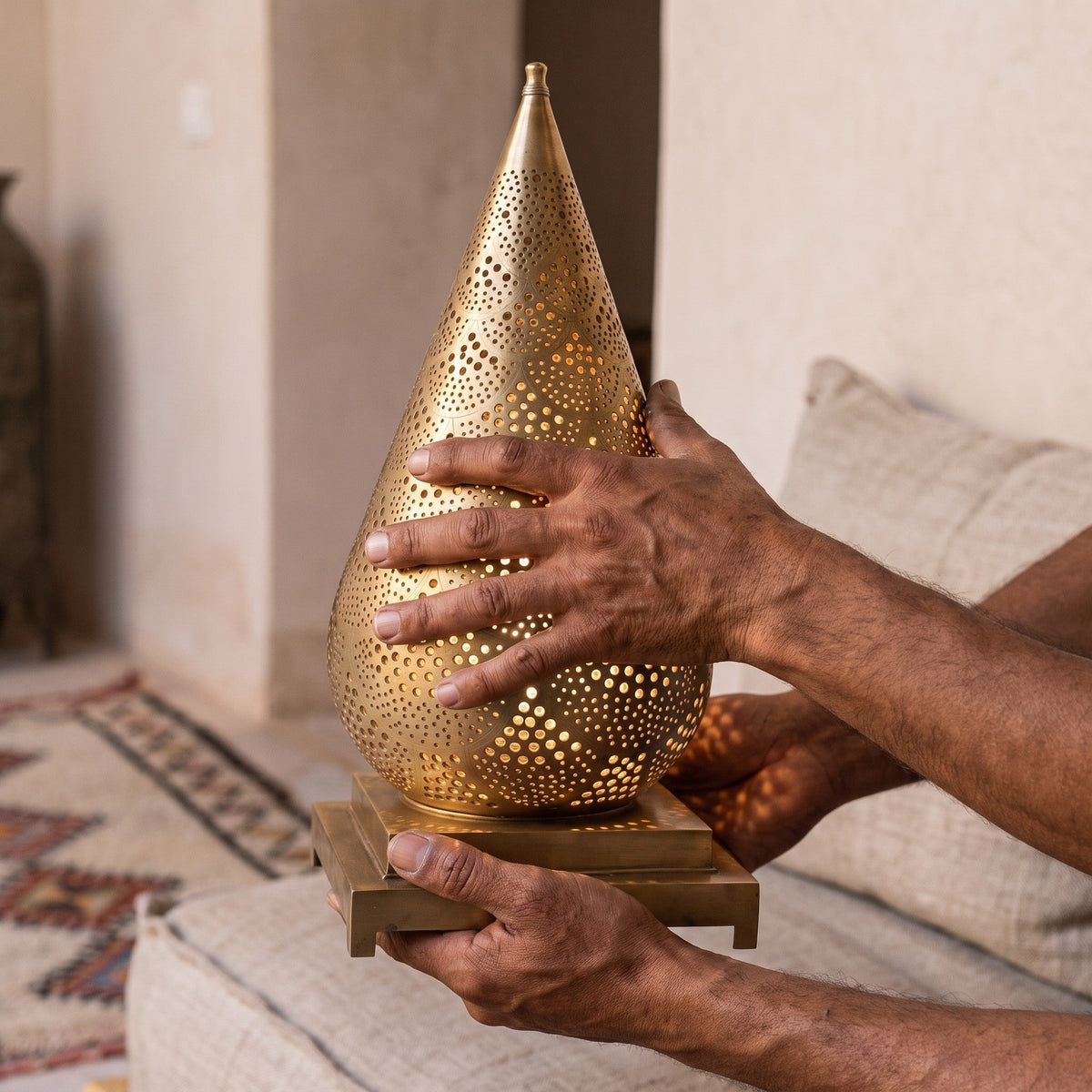 Artisan's hands holding the Siraj lantern, piercing visible up close