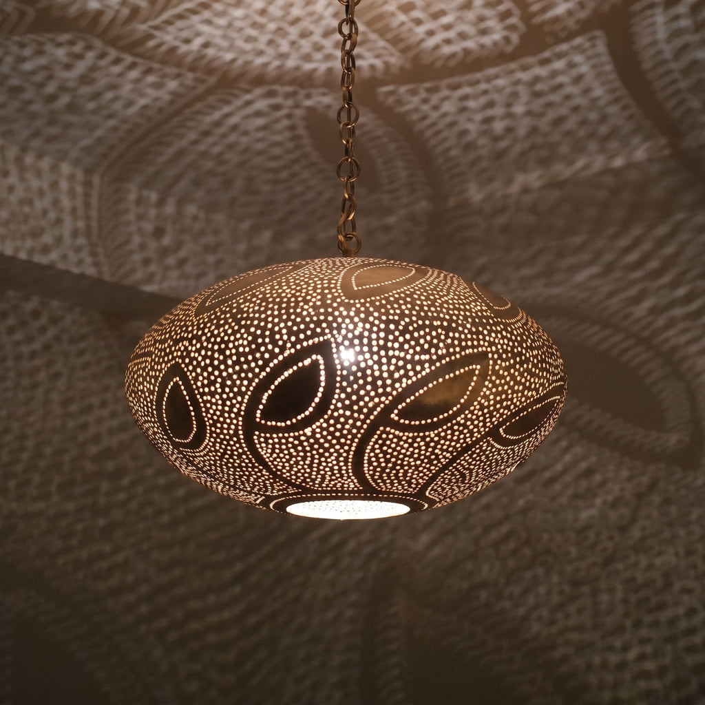 Close detail of the lit Souhail pendant, leafwork pierced through the brass