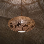 Close detail of the lit Souhail pendant, leafwork pierced through the brass