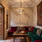 Souhail pendant glowing under a riad ceiling, its pattern thrown upward