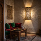 Two Sqala sconces lit on a stone-toned wall in a Moroccan riad