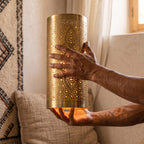The maker's hands holding a Sqala sconce shade of pierced brass