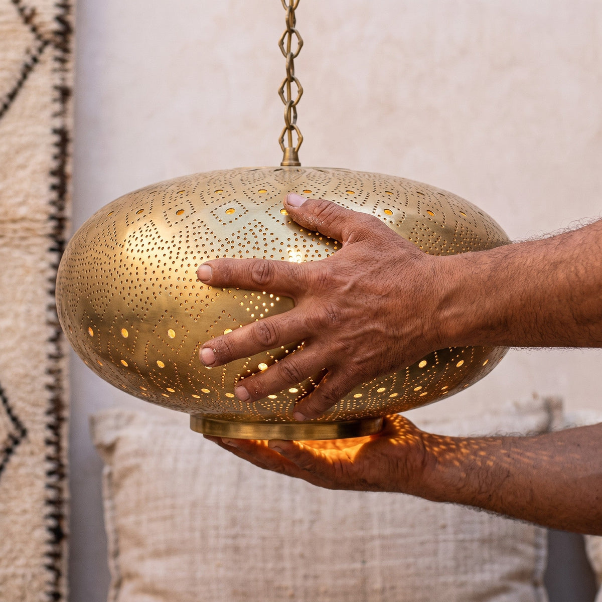 Maker's hands holding the hand-pierced Tafat shade