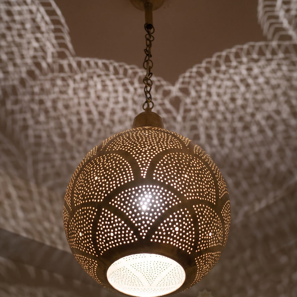 Close detail of the lit Tanirt pendant, punched circles glowing in the brass