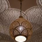 Close detail of the lit Tanirt pendant, punched circles glowing in the brass