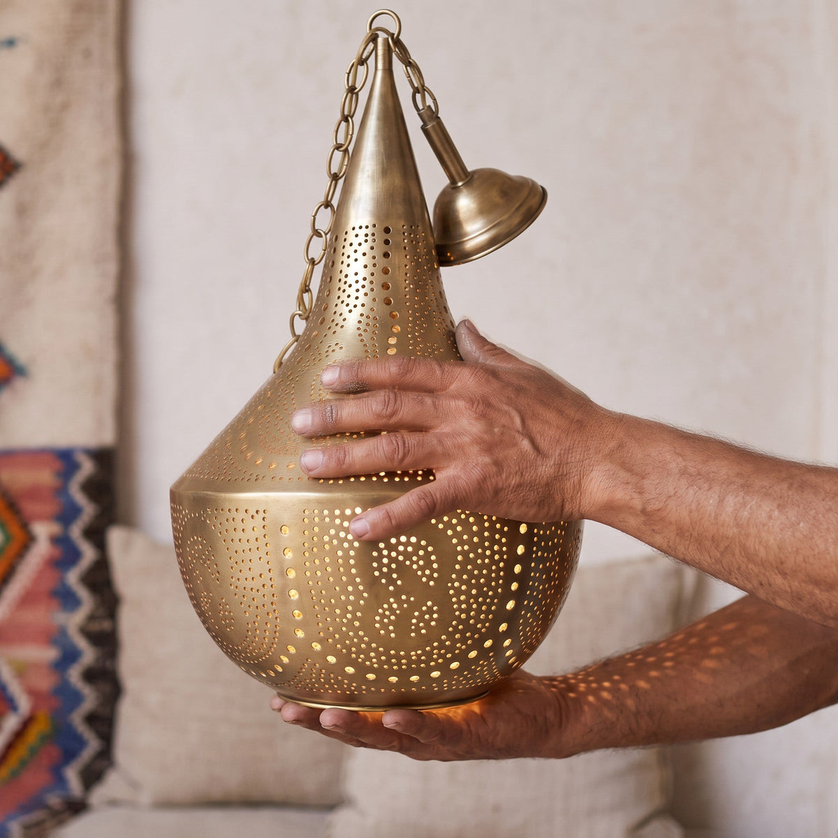 Artisan's hands holding the tall Telouet brass shade